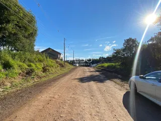 Uma estrada de terra leva a uma área rural com vegetação.