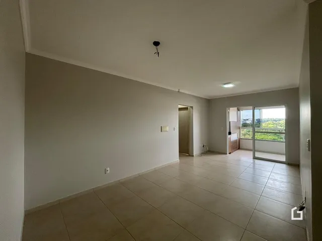 Interior de uma sala ampla com piso de cerâmica e paredes brancas.