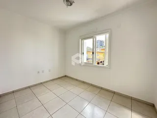 Ambiente interno de uma sala com piso de cerâmica e janela.
