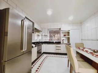 Interior de uma cozinha com armários brancos e piso escuro.