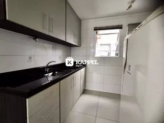 Cozinha moderna com armários brancos e bancada escura.