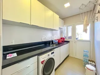 Vista da cozinha com armários brancos e bancadas escuras.