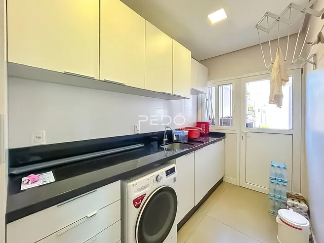 Vista da cozinha com armários brancos e bancadas escuras.