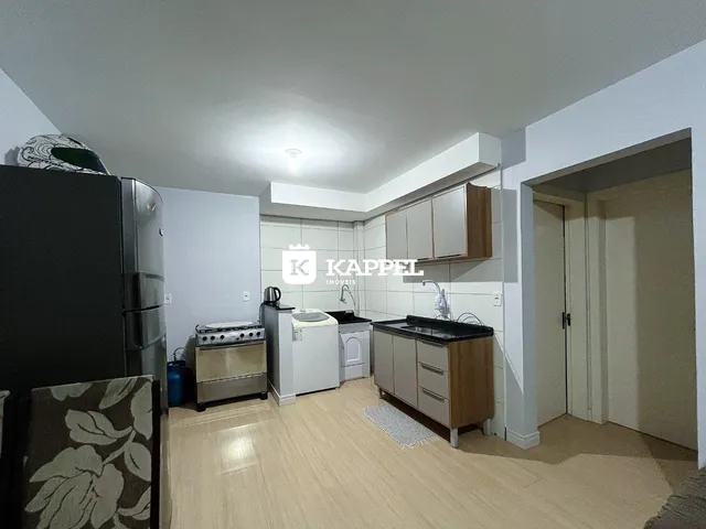 Foto interna de uma cozinha com armários de madeira e piso claro.