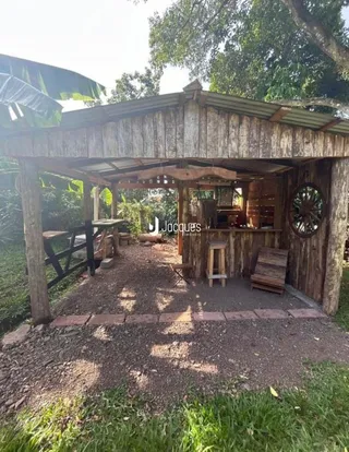 Uma área externa coberta com estrutura de madeira e vegetação densa.