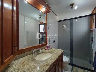 Foto de um banheiro com bancada e box de vidro.