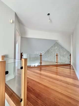 Vista de um ambiente interno com piso de madeira e divisória de vidro no imóvel.
