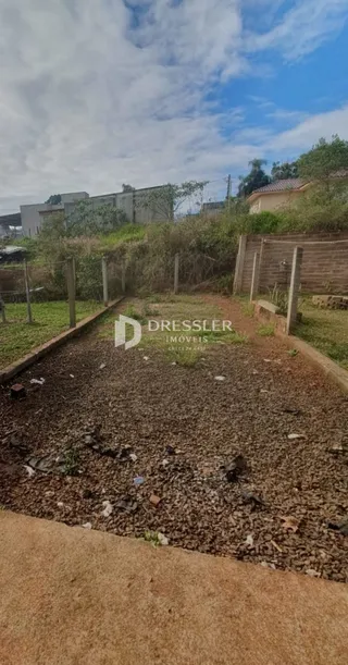 Vista externa de um terreno com cerca de madeira e vegetação