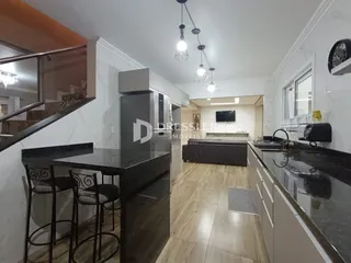 Vista de uma cozinha moderna com bancadas de mármore e piso de madeira.