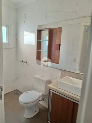 Foto de um banheiro com revestimento branco e louças sanitárias.