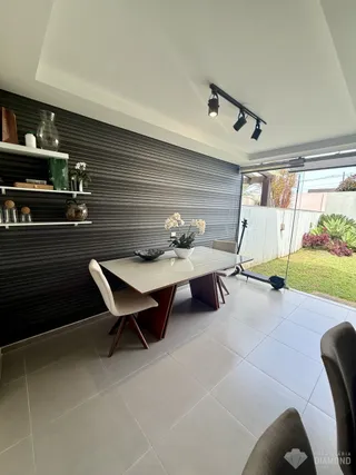 Vista de uma sala de jantar com mesa de vidro e vista para o jardim.
