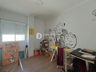 Ambiente interno de uma sala com piso de madeira clara e parede branca.
