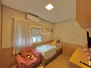 Quarto com cama e poltrona em ambiente claro.