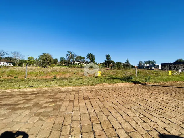 Vista externa de uma propriedade com terreno gramado e pavimentação de tijolos.