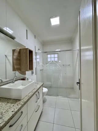 Foto de um banheiro com bancada de granito e box de vidro transparente.
