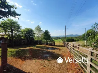 Vista externa de um terreno com vegetação e cerca de madeira.