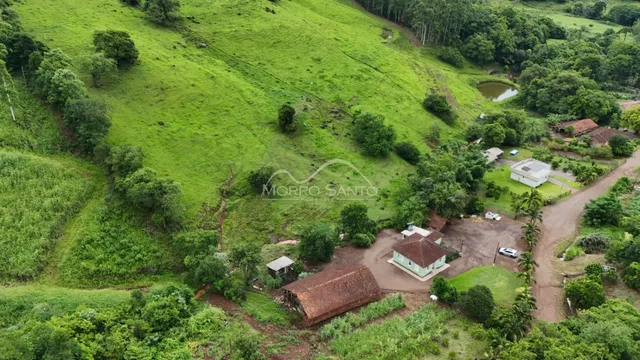Vista aérea de uma propriedade com colinas verdes e vegetação.
