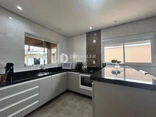 Cozinha moderna com armários brancos e bancadas escuras.