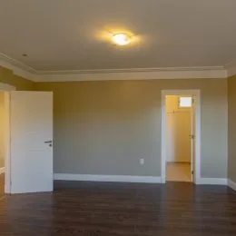 Interior de uma sala com piso de madeira e porta.