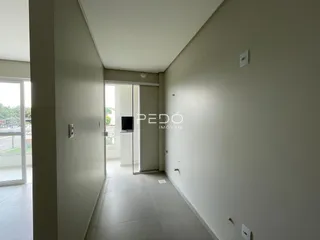 Corredor interno de um imóvel com paredes claras e piso claro.