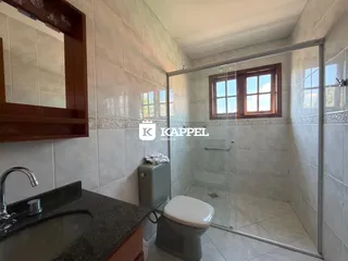 Banheiro com box de vidro e revestimento de azulejos brancos.