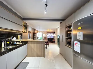 Cozinha moderna com armários brancos e bancadas escuras em um apartamento em Lajeado.