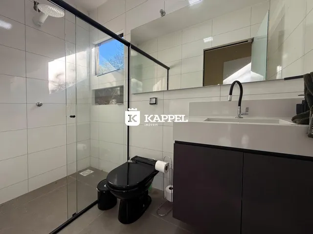 Banheiro com box de vidro e louças sanitárias.