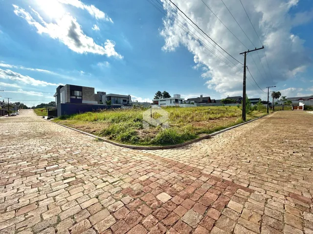 Vista externa da propriedade com jardim e calçada de paralelepípedos.