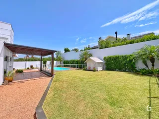 Vista externa de um quintal com gramado e piscina.