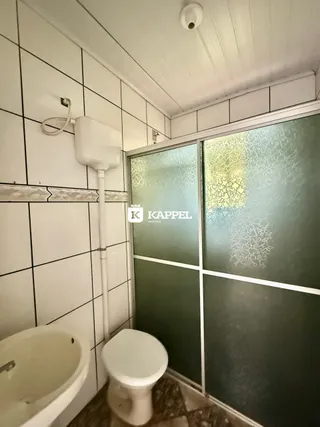 Banheiro com revestimento de azulejos brancos e vaso sanitário branco.