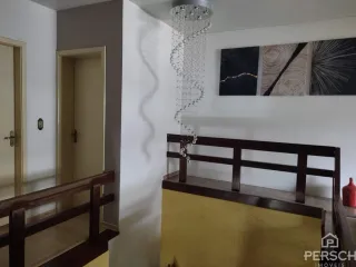 Hall de entrada com corrimão de madeira e parede branca.