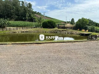 Vista de um lago cercado por vegetação e cerca rústica.