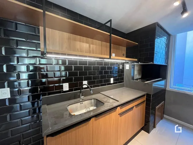 Foto de uma cozinha moderna com revestimento de azulejos pretos e armários de madeira clara.