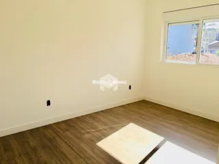 Interior de uma sala com piso de madeira e janela.
