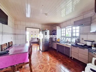 Foto interna de uma sala de jantar e cozinha com piso de madeira e revestimento de azulejos.