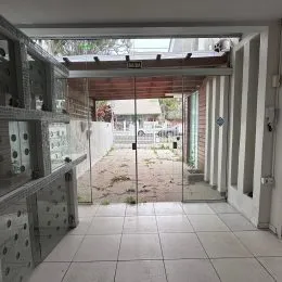Foto de um corredor interno com portas de vidro e piso de cerâmica.