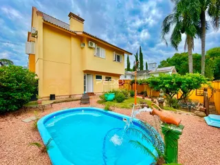 Vista da fachada de uma casa amarela com piscina no quintal.