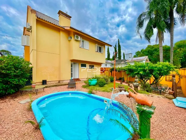 Vista da fachada de uma casa amarela com piscina no quintal.