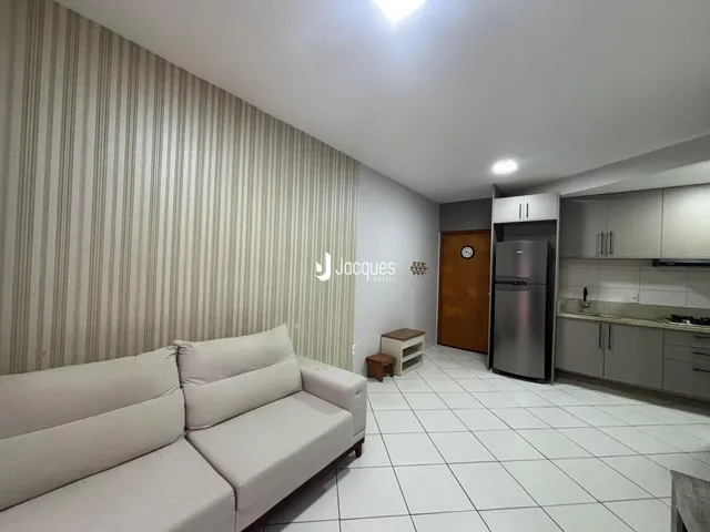Sala de estar com sofá branco e piso cerâmico claro.