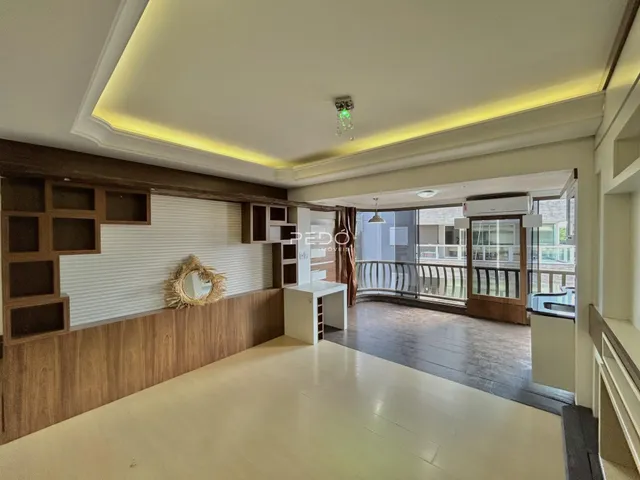 Ambiente interno de uma sala de estar com painéis de madeira e vista para a varanda.