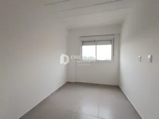 Foto interna de um cômodo com paredes brancas e uma janela.