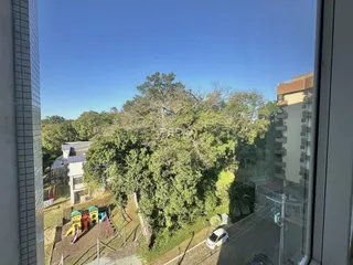 Vista externa de uma propriedade com vegetação densa e área de lazer ao fundo.