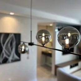 Hall de entrada com paredes brancas e luminárias pendentes.