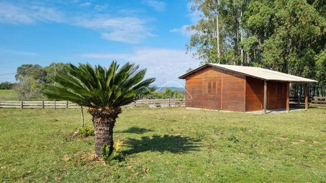 Fachada de uma cabana de madeira em um campo gramado no exterior.