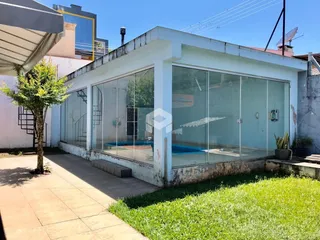 Fachada moderna de uma residência com grandes janelas de vidro e jardim.