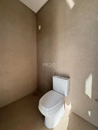 Foto interna de um banheiro com revestimento de cerâmica e vaso sanitário branco.