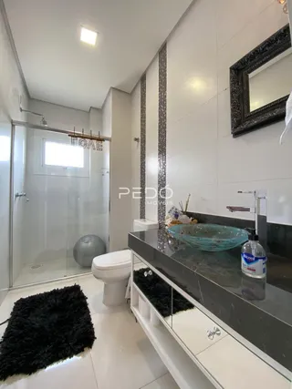 Foto de um banheiro moderno com revestimento branco e bancada escura.