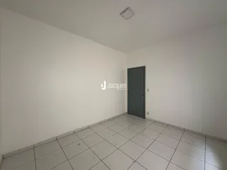 Ambiente interno de uma sala com piso de cerâmica e parede branca.