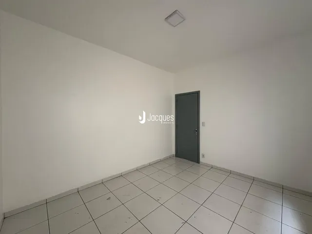 Ambiente interno de uma sala com piso de cerâmica e parede branca.