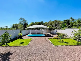 Área externa com piscina e gramado cercada por muro branco.
